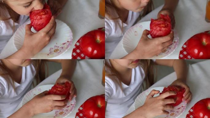 有趣的小女孩坐在厨房的桌子上，吃有机蔬菜成熟的红番茄。
