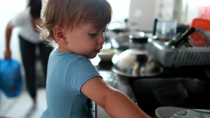 Tip脚在厨房水槽上的婴儿蹒跚学步，帮助家庭主妇