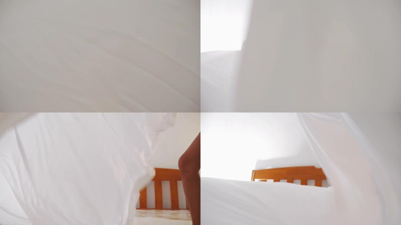 快乐的亚洲女孩和床上用品用白色床单和羽绒被与她的兄弟，生活方式的概念。
