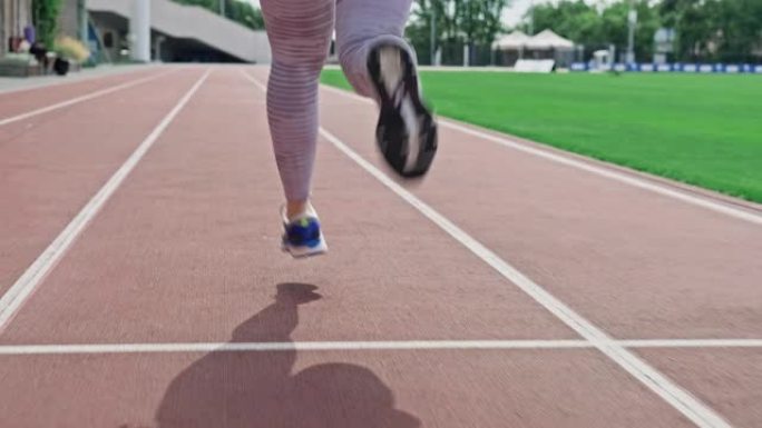 追踪在体育场赛马场跑步的女人的腿。运动鞋的特写。