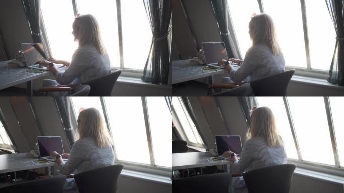 在渡轮上使用笔记本电脑的金发女人