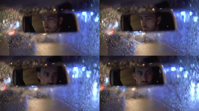 迷人的男人在雨夜坐在车里