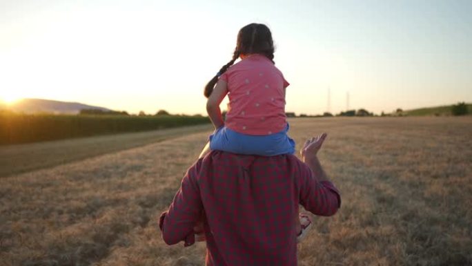 父亲带着女儿在日落时穿过麦田，日落时穿过麦田