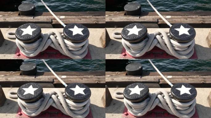 系绳结在金属系柱上的星星，加利福尼亚州圣地亚哥的航海港口。停泊在船坞的航海船。锚索系带固定在码头上。