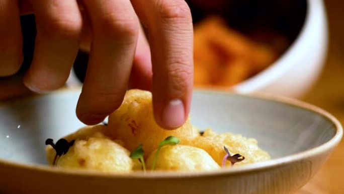 手在盘子里拿一个炸丸子。完美的西班牙小吃，酒吧或餐馆的传统食物 -- 特写
