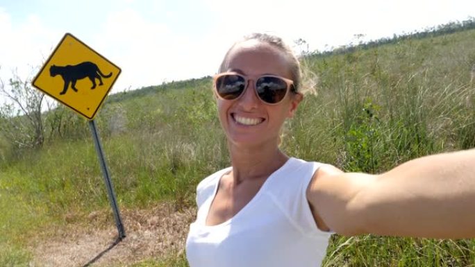 年轻女子在佛罗里达黑豹警告标志附近空荡荡的高速公路上自拍