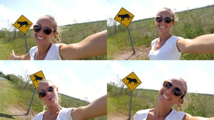年轻女子在佛罗里达黑豹警告标志附近空荡荡的高速公路上自拍