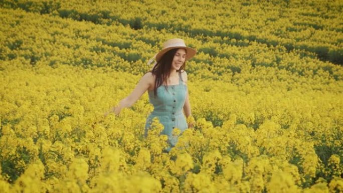 快乐年轻美丽的女人走在黄色花田油菜籽上，盛开
