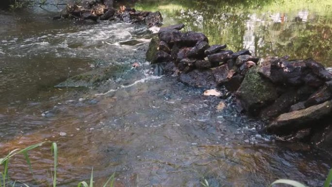 清澈的水通过石头在河中流动。慢动作镜头