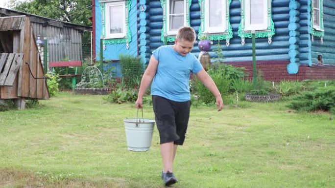 这个男孩从井里提着一个装满水的重水桶。