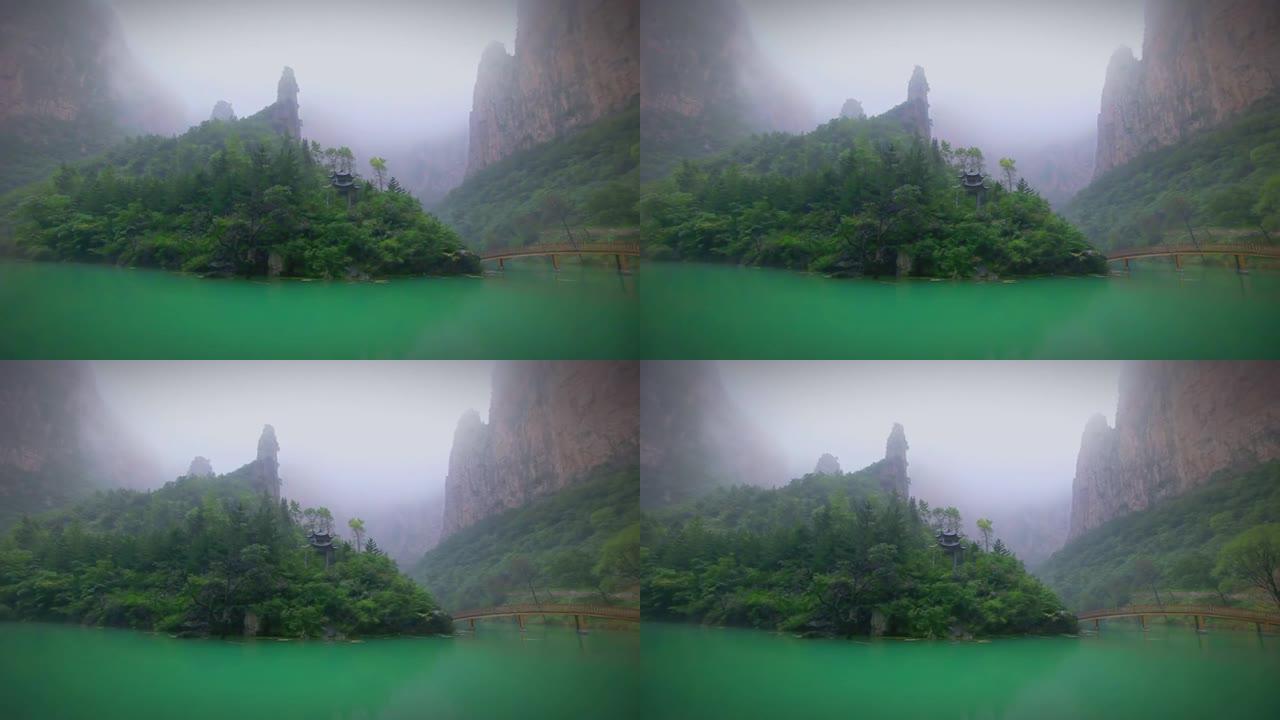 小亭子隔着一个小湖。雾中覆盖着绿色雨林的山脉和岩石令人惊叹。