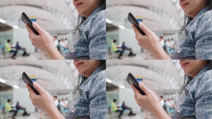 亚洲女旅客在机场航站楼候机时使用手机