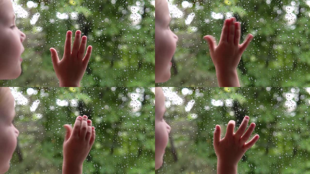 小女孩看着窗外的雨水和绿树。手放在玻璃上。
