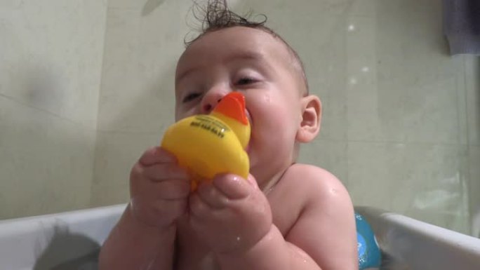 浴缸里可爱的可爱宝宝把黄鸭放进嘴里