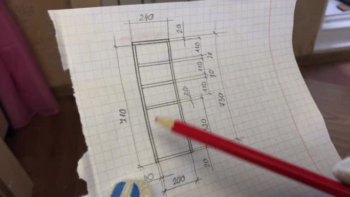 一名男子检查由木板制成的架子的图纸。在图像上画一支铅笔。在家做家具。