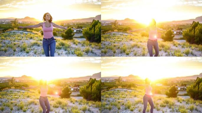 迷人的年轻女子在日落时张开双臂在山顶旋转。