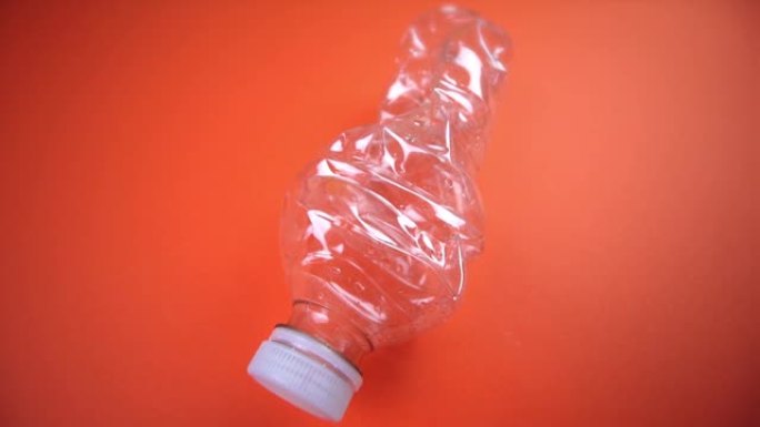 带盖的压碎塑料瓶放在鲜橙色上