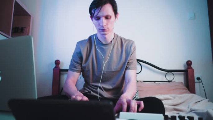 年轻的高加索人坐在卧室里，用MIDI键盘或合成器演奏，制作电子音乐。Dj慢动作镜头