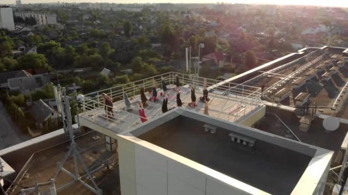 一群妇女与一名教练在建筑物屋顶的培训课程中伸展并在瑜伽垫上训练