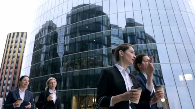 女性商业团体走过现代办公楼的低角度视角。喝咖啡与客户银行财务HR讨论商业案例，自信的女性领导者，未来