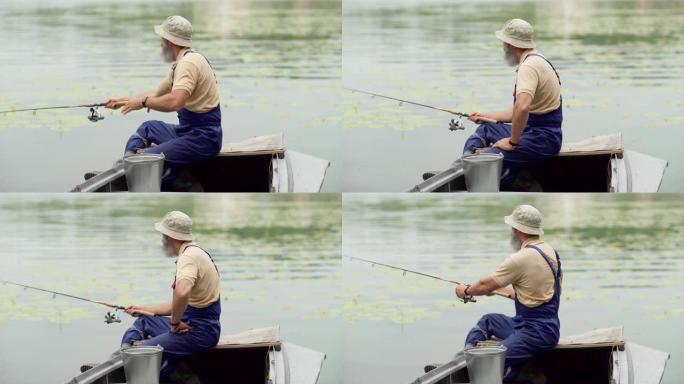 坐在木船上在湖里钓鱼的大胡子老渔夫的侧视中等镜头
