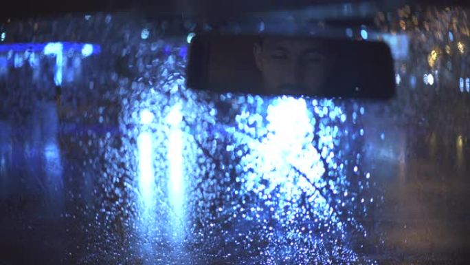 这个年轻人在下雨的夜晚坐在车里