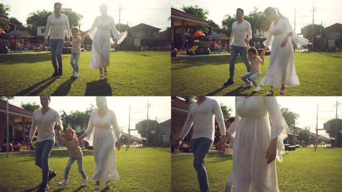 亚洲家庭快乐地牵着手在公园散步夏天。父亲和女人在户外与她迷人的小女儿共度时光