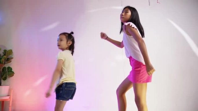 快乐的亚洲女孩在家庭派对上跳舞，搭配led灯，生活方式理念。
