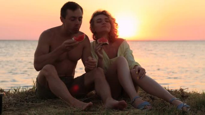 坐在海边吃西瓜的夫妇