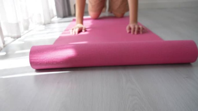 在地板上滚动粉色瑜伽垫。