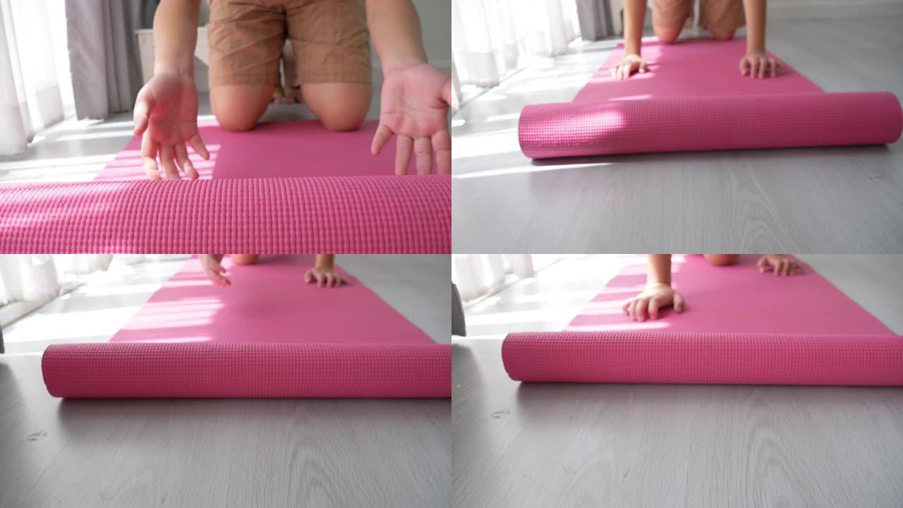 在地板上滚动粉色瑜伽垫。