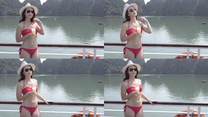 年轻女子在船上享受着一杯果汁，亚洲下龙湾，越南