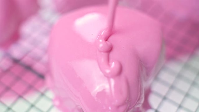 将粉红釉糖霜以心形倒在冷冻的粉红蛋糕上