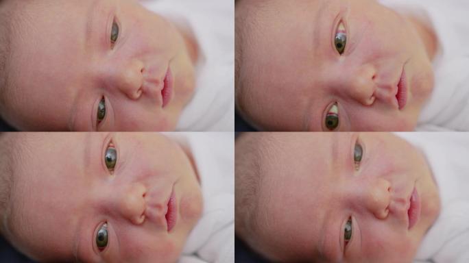 特写初生婴儿醒来睁开眼睛的脸。一个刚出生的婴儿在梦中做鬼脸。出生的最初几分钟。