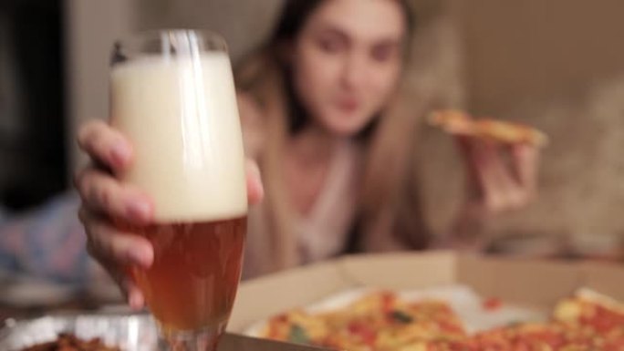 女孩吃披萨，喝啤酒，然后把杯子放回桌子上。