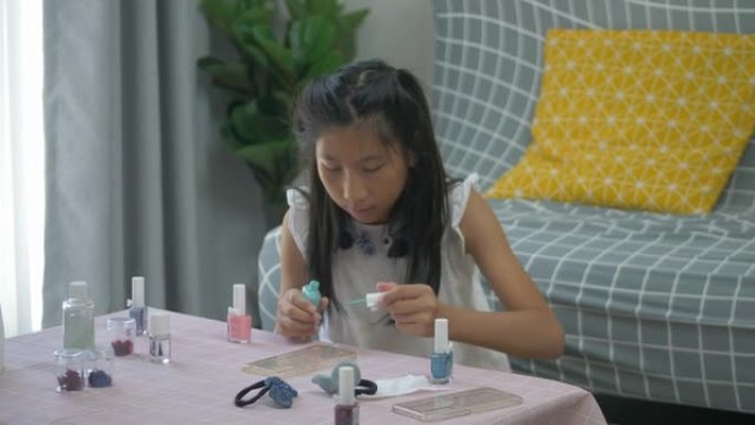 快乐亚洲女孩在家涂指甲油手机套，DIY概念。