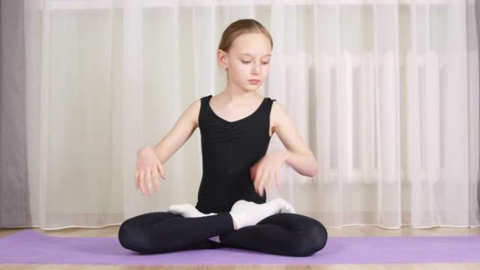 坐在莲花里的年轻女孩在家庭瑜伽训练中摆姿势。适合年轻女子在地毯上训练瑜伽体式。练习萨哈萨纳·阿萨纳。