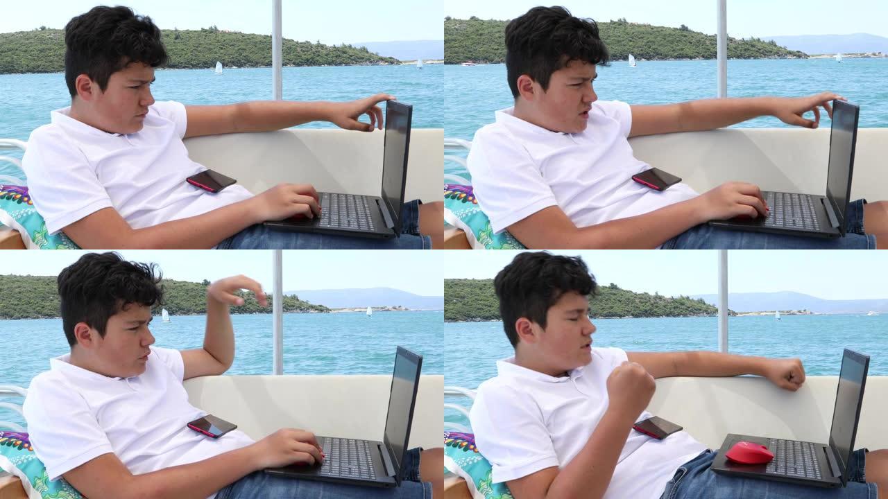 游艇甲板上使用笔记本电脑的小男孩