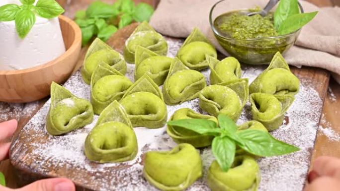 意大利。食物背景与自制的意大利意大利饺子和木质背景上的绿色香蒜酱成分。高角度视图。复制空间。