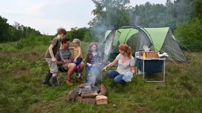 有三个孩子的家庭在篝火上烧烤食物