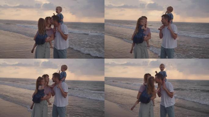 年轻的父母站在海边，抱着他们的小孩，亲吻