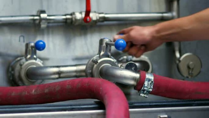 带橡胶管的锅炉系统保持蓝色水平的啤酒制造工人的作物视图