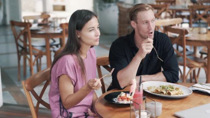 恋人男人和女人坐在户外咖啡馆里，吃健康的食物和聊天