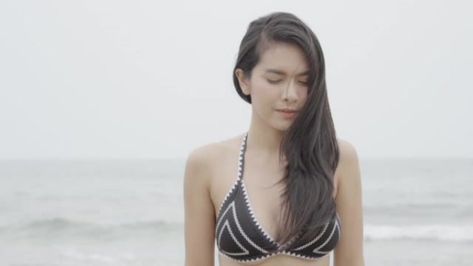 穿着比基尼的美丽晒黑的年轻亚洲女性在海滩上嬉戏，女孩性感快乐，夏天度假时微笑，女人穿着热带泳装或泳装