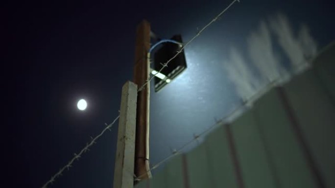 夜间带照明和铁丝网的安全周边围栏。