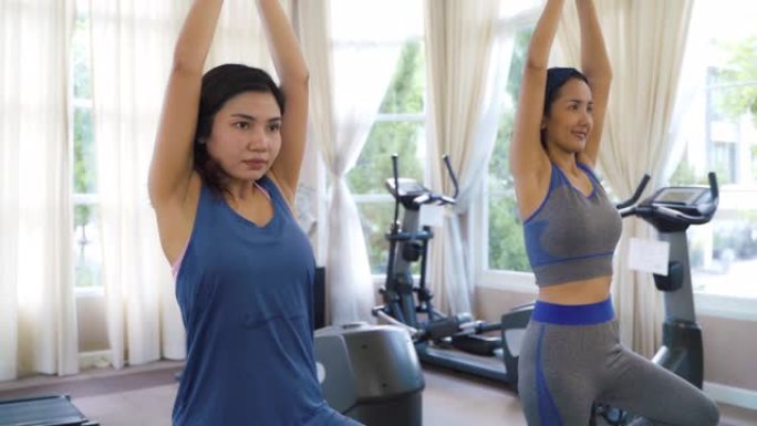 两名亚洲女性在运动服训练锻炼和练习瑜伽，教练为健康的生活方式。