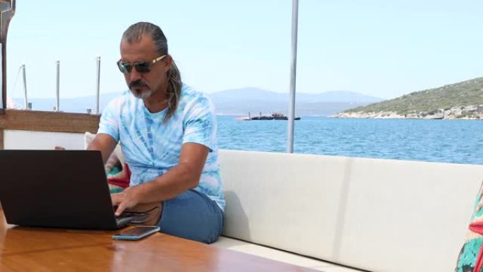 在游艇甲板上使用笔记本电脑的商人