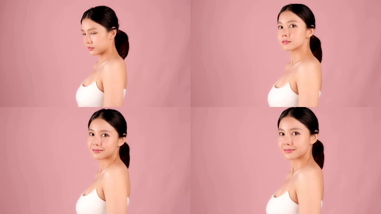 慢动作美女拍摄美丽的亚洲女孩看着相机孤立在粉红色背景