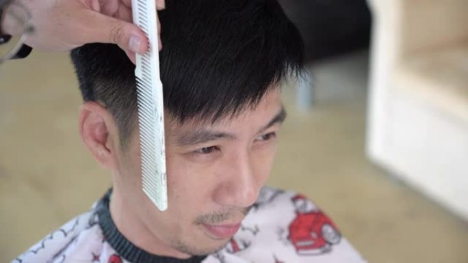 亚洲男子在家被剪发剪发的侧视图。