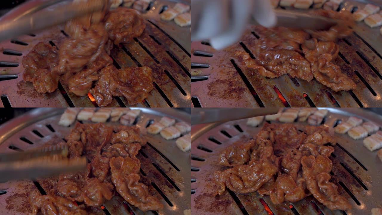 在餐厅的韩国铁烧烤烤盘上，厨师手工烹饪猪肉切片和韩国红酱的4k特写镜头。传统韩国风格的食物烧烤炉上的